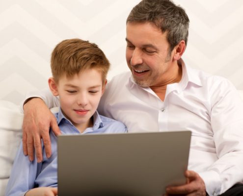 father and son who has expressive language disorder on a laptop