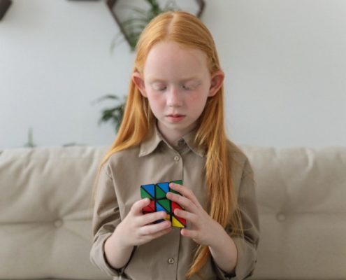 a child playing with a rubik's cube to help promote her speech therapy at home