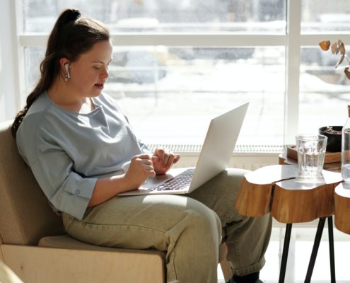 Teenage girl with special needs using her laptop next to a window