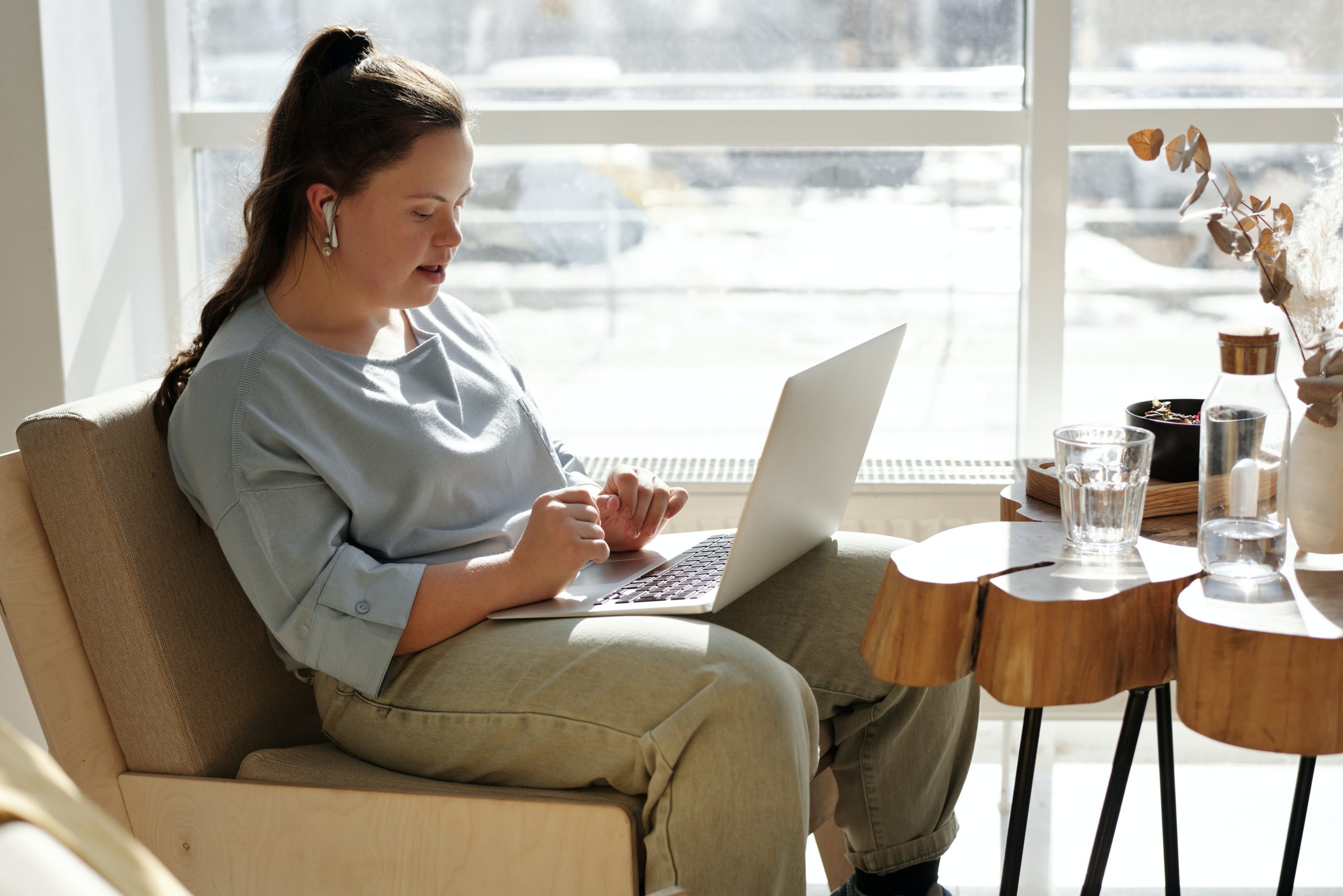 Teenage girl with special needs using her laptop next to a window