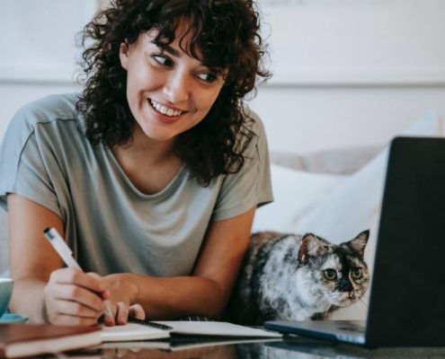 a woman with pen and paper researching lisp disorders while smiling