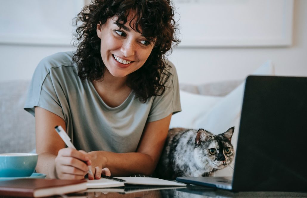 a woman with pen and paper researching lisp disorders while smiling