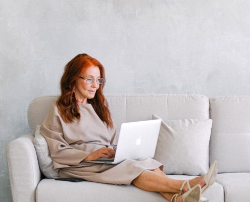 A woman researching Huntington's disease symptoms from her couch at home