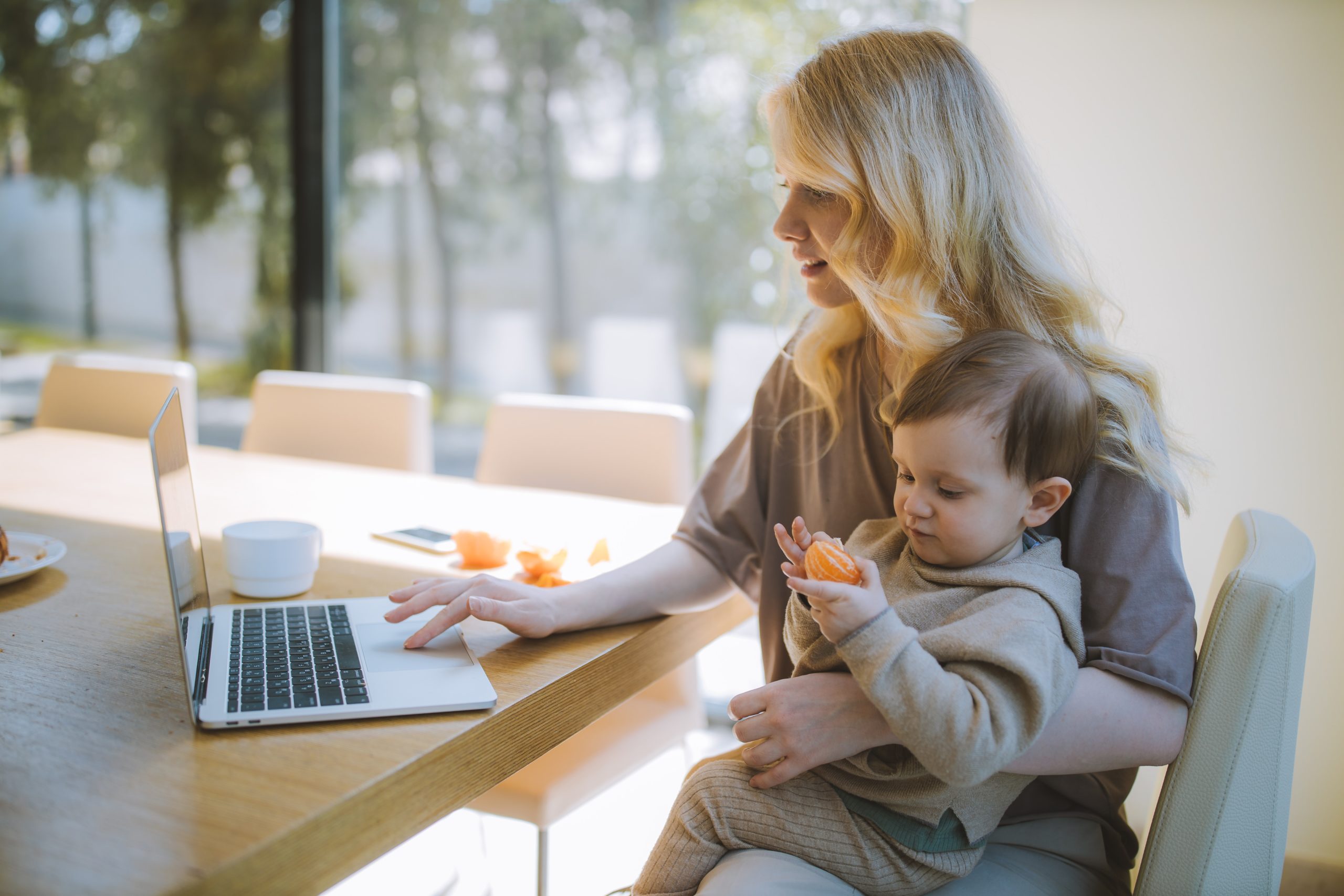 a young child learning from home on a laptop with a mother