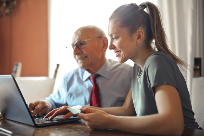 a woman helping her grandfather who suffers dementia on the computer at home