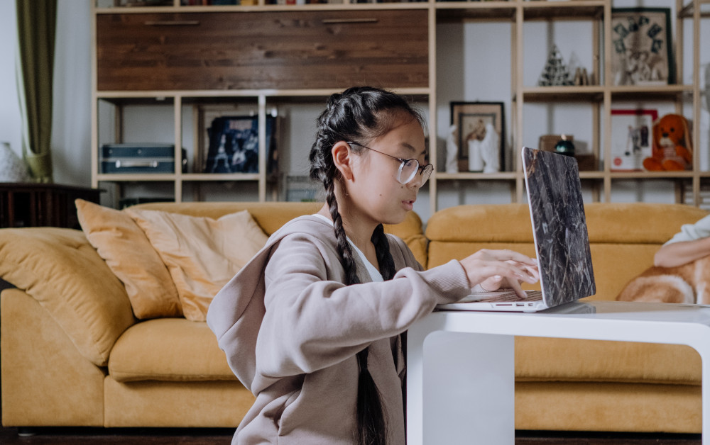 a girls at home working on her speech via a laptop