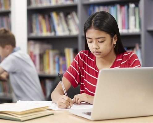 Female High School Student Working At Laptop In Library representing Benefit from Speech and Language Therapy