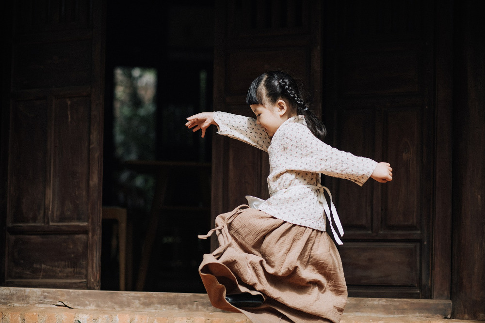 a child in traditional dress dancing and looking happy
