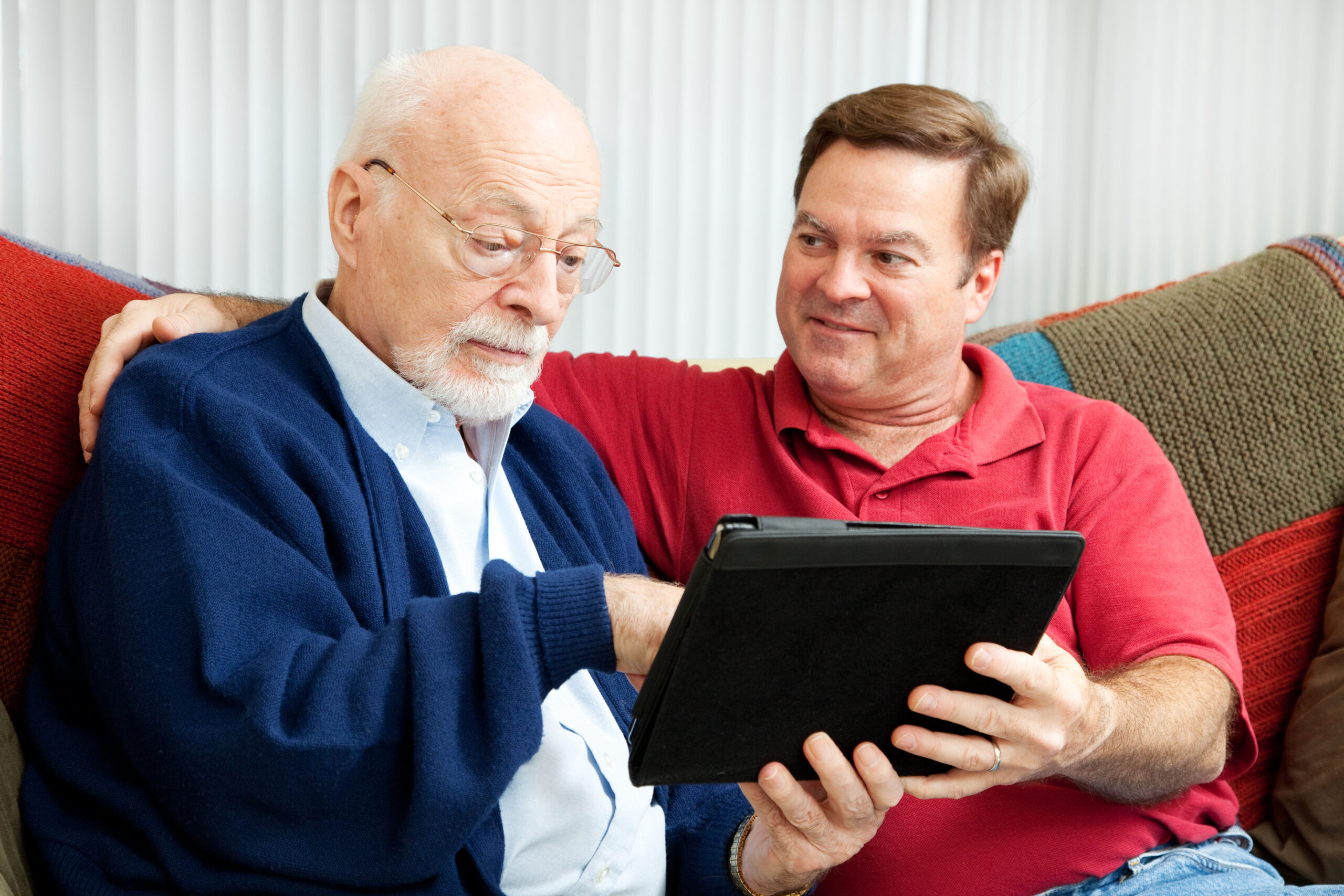man teaching his father to use a tablet