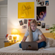 a teenage girls sitting on her bed with a laptop