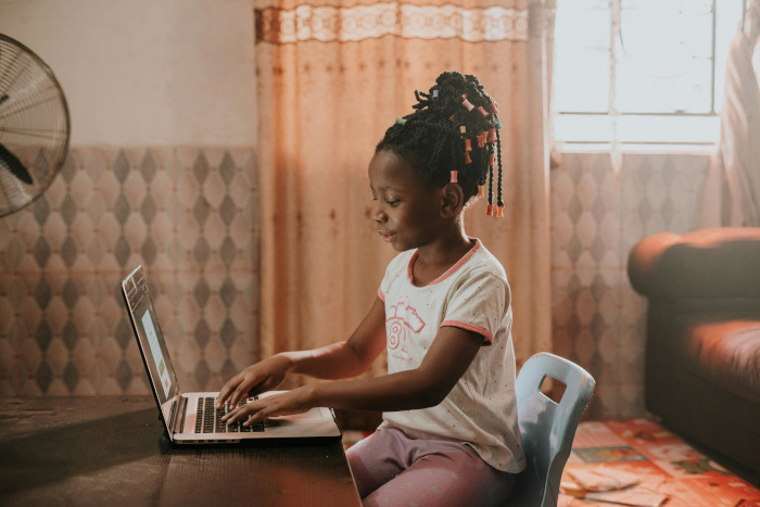 a girl at home on her laptop doing online speech therapy