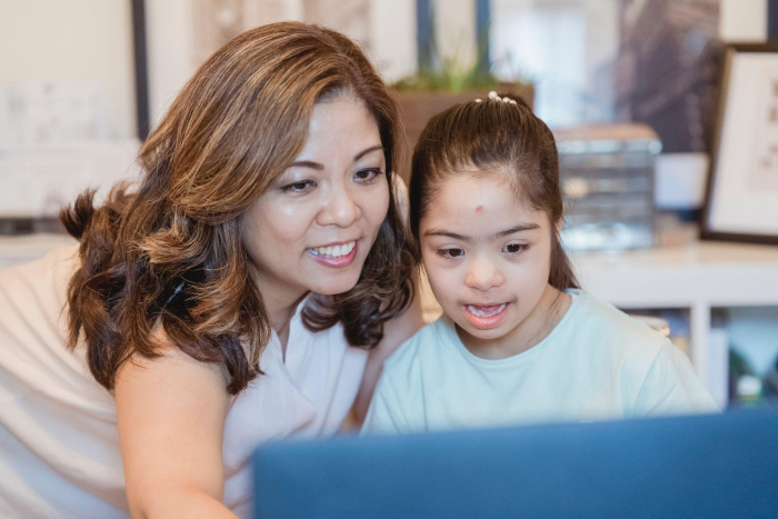 A girl with down syndrome conducting online speech therapy session from her laptop at home