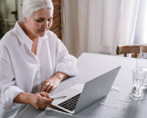an elderly woman on her laptop working on her language difficulties