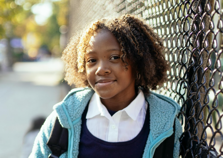 a girl standing in front of a metal fence